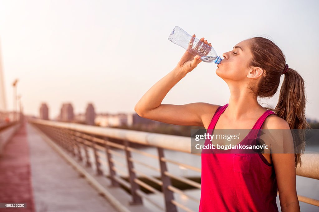 Sportswoman hydrating on the bridge