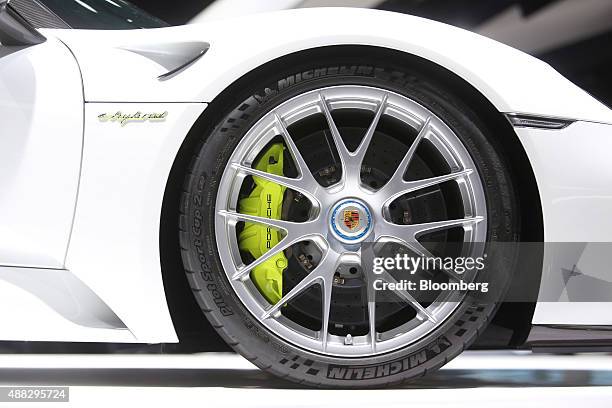 The Porsche badge sits on a wheel hub of a Porsche AG 918 Spyder e-hybrid automobile, produced by Volkswagen AG , sits on display during previews for...