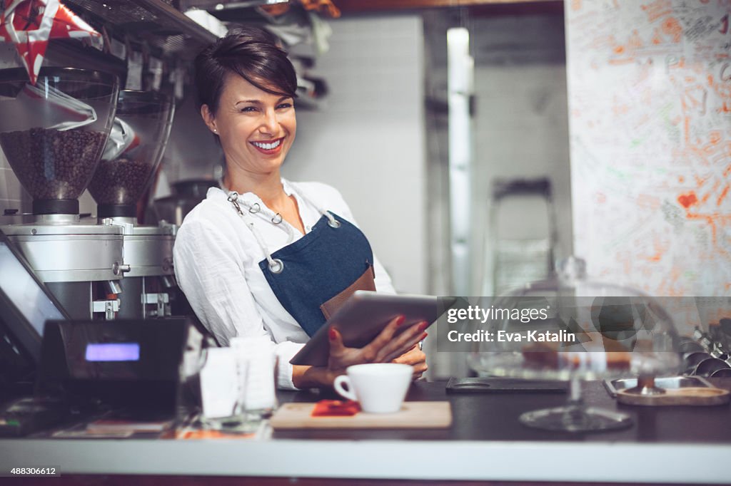 Young barista está usando una tableta digital