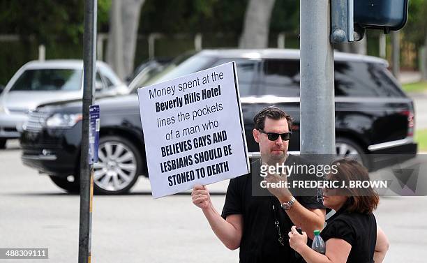 Supporter of women's rights and LGBT groups holds a placard in protest at a street corner across from the Beverly Hills Hotel, owned by the Sultan of...