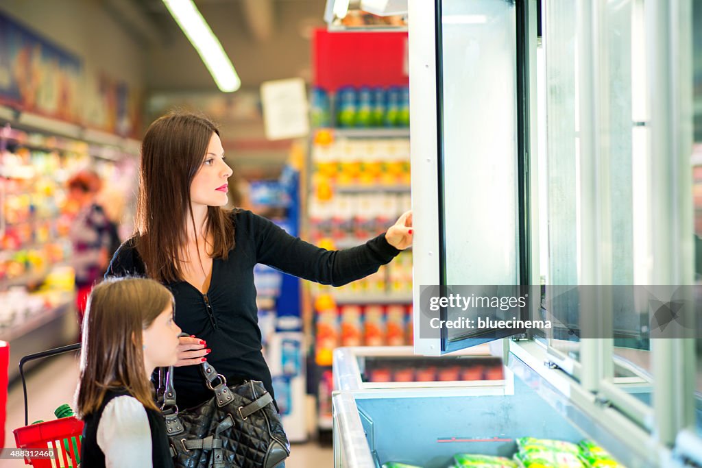 Mother and daughter in supermarket near frozen food