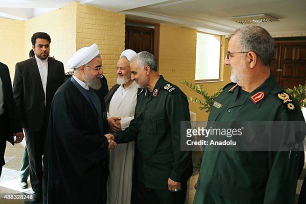 Iranian President Hassan Rouhani shakes hands with Iranian Quds Force commander Qassem Soleimani as Revolutionary Guards' ground forces commander...