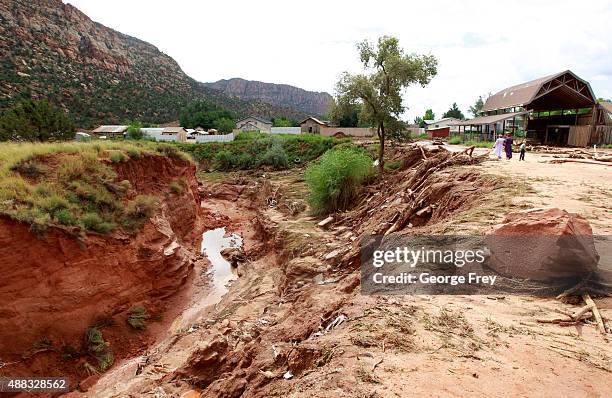 People walk along the edge of a gully at the spot where two vans were swept away the day before into Short Creek on September 15, 2015 in Hildale,...