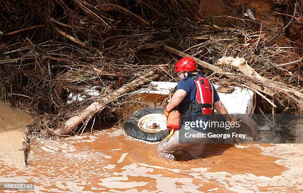 Search and rescue member searrches a buried vehicle in Short Creek where two vans were swept away the day before on September 15, 2015 in Colorado...