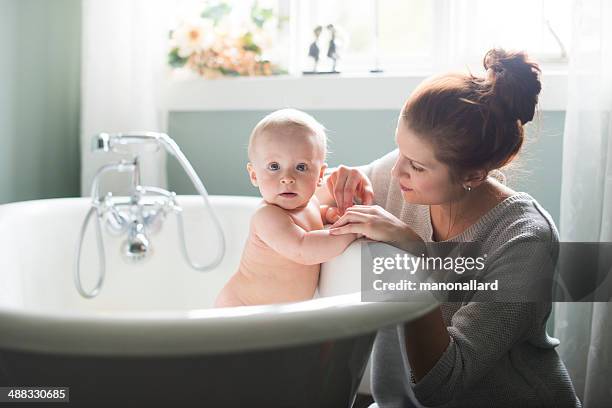 mom giving baby bath - mother and baby taking a bath stock pictures, royalty-free photos & images