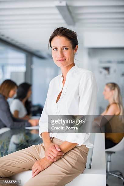 businesswoman sitting on conference table - dreiviertelansicht stock-fotos und bilder
