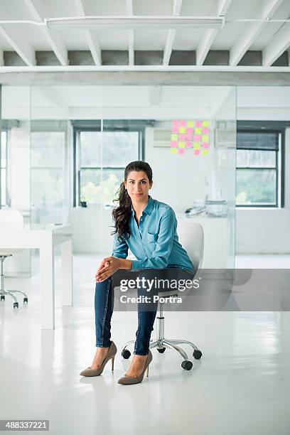 businesswoman sitting on a chair in open office - office chair stockfoto's en -beelden