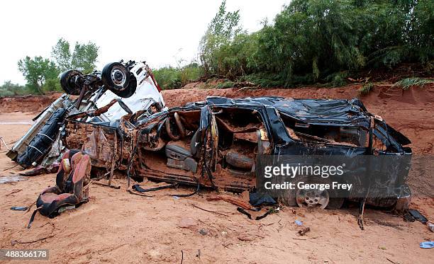 The twisted wreckage of two vans that were washed away in a flash flood with women and children inside rest on the bank of Short Creek on September...