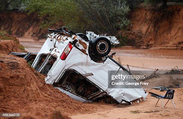 The twisted wreckage of one of two vans that were washed away in a flash flood with women and children inside rest on the bank of Short Creek on...