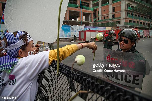 Activist Yorm Bopha offers a lotus flower to a Cambodian police officer in front of barricades set up to impede access to the Municipal Court on May...