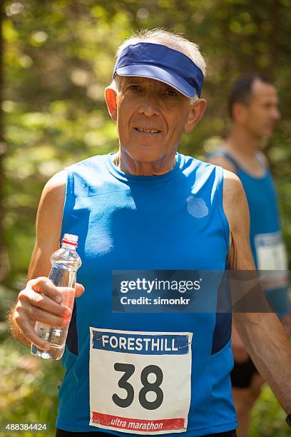 man holding water bottle during ultramarathon race training - bib stock pictures, royalty-free photos & images