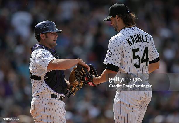 Catcher Michael McKenry delivers the ball to relief pitcher Tommy Kahnle of the Colorado Rockies as they face the New York Mets at Coors Field on May...
