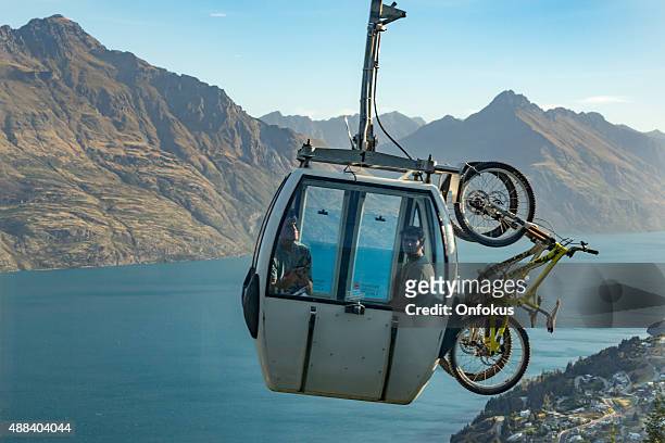 mountain bikers in skyline gondola going over queenstown city - the remarkables stock pictures, royalty-free photos & images