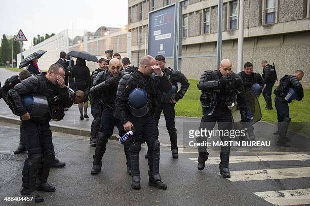 French Gendarmes wipe their eyes after using tear gas to free an entrance for vans transporting prisoners blocked by French prison guards who...