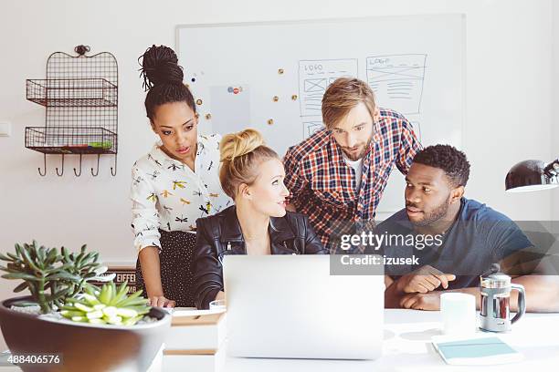 arranque agencia, multi étnica equipo de discusión de ideas, el uso de una computadora portátil - persuasión fotografías e imágenes de stock