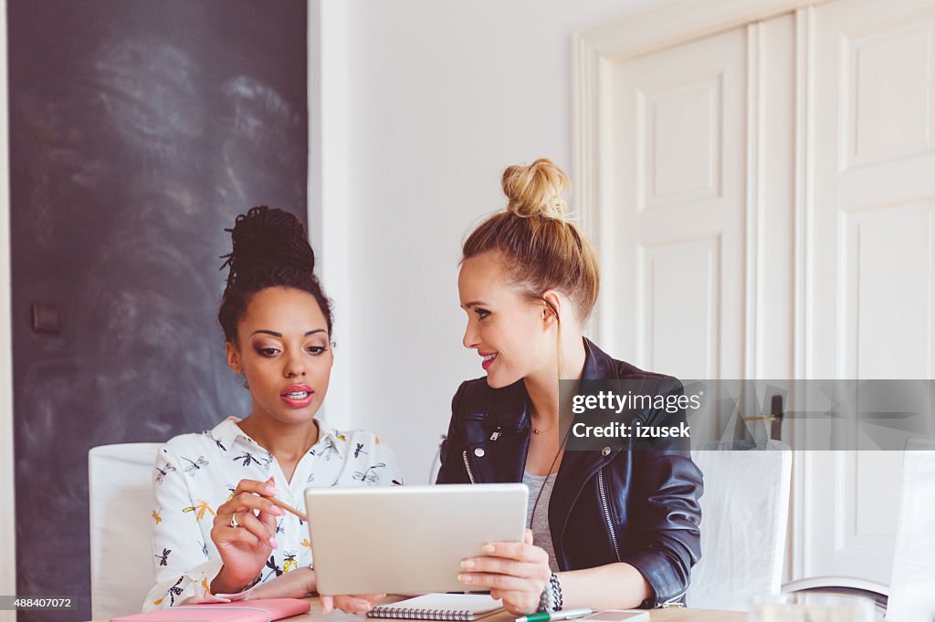 Dos mujeres trabajando en tableta digital en una oficina