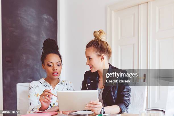 deux femmes travaillant sur tablette numérique dans un bureau - influencer photos et images de collection