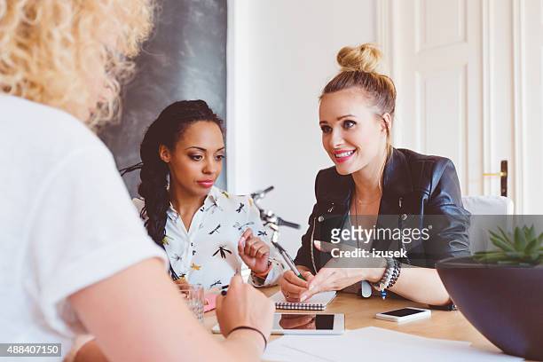 three women discussing in an office - influence stockfoto's en -beelden