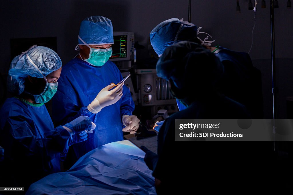 Surgeon using sutures during operation in hospital operating room