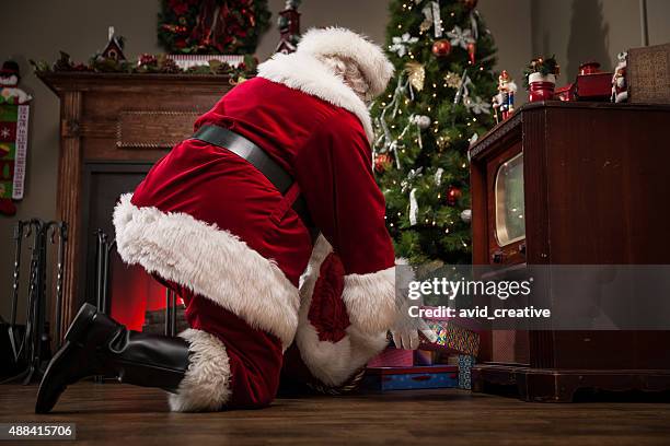 real santa delivering gifts - gift under christmas tree stock pictures, royalty-free photos & images