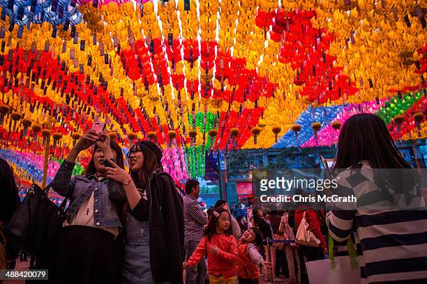 People take selfies and play under lines of lit lanterns after the Vesak Buddhist Ceremony celebrating Buddha's birth at the Jogyesa Temple on May 6,...