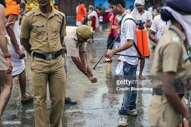 Street cleaner carrying a spray pack of Dettol disinfectant, produced by Reckitt Benckiser Group Plc, assists a police officer cleaning his hands in...