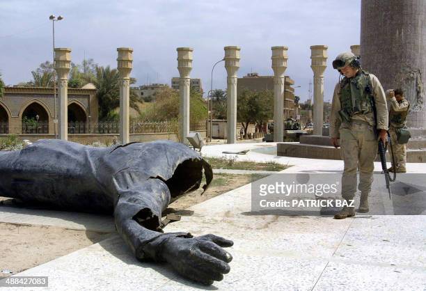 Marines walk pass a dismounted statue of Saddam Hussein on Baghdad's al-Fardous square 10 April 2003. As the regime of Saddam Hussein collapsed,...