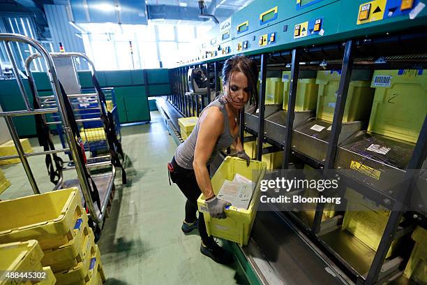 An employee collects pre-sorted mail for delivery in crates from a sorting machine inside a Poste Italiane SpA postal sorting office in Fiumicino,...