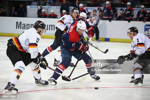 Craig Smith of USA is challenged by Tobias Rieder and Justin Krueger of Germany during the international ice hockey friendly match between Germany...