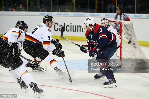 Craig Smith of USA is challenged by Justin Krueger and Tobias Rieder of Germany during the international ice hockey friendly match between Germany...