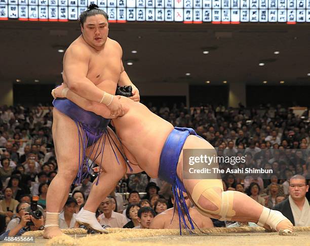 Ozeki Kotoshogiku pushes Okinoumi out of the ring to win during day four of the Grand Sumo Autumn Tournament at Ryogoku Kokugikan on September 16,...