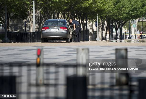 Police officer searches a car on Pennsylvania Avenue near the White House May 6, 2014 in Washington, DC. The area was locked down after the car was...