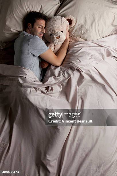 man sleeping in bed with his teddy bear - soft toy fotografías e imágenes de stock