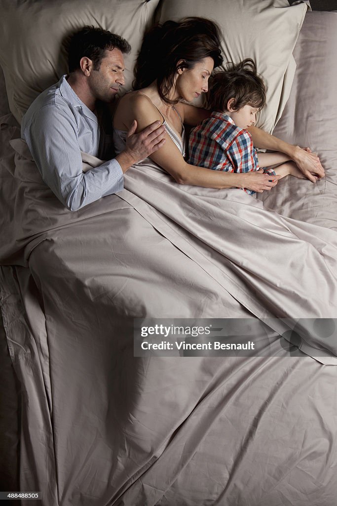 Couple lying in a bed with children
