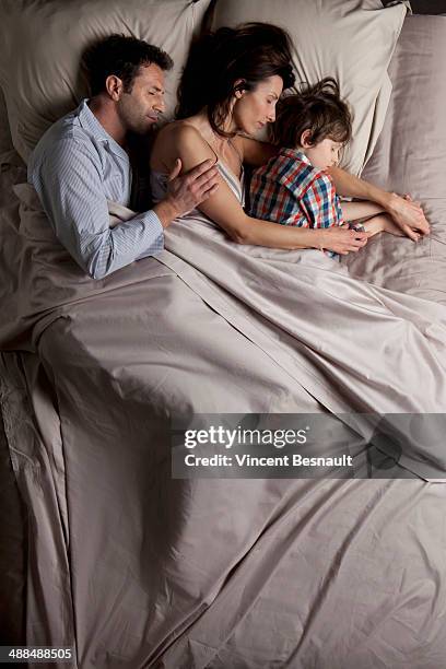 couple lying in a bed with children - vincent young stock pictures, royalty-free photos & images