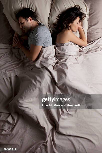 woman and a man lying back to back in bed - linge de lit photos et images de collection