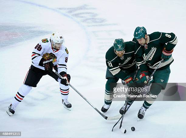 Kyle Brodziak and Cody McCormick of the Minnesota Wild controls the puck against Patrick Kane of the Chicago Blackhawks during the first period in...