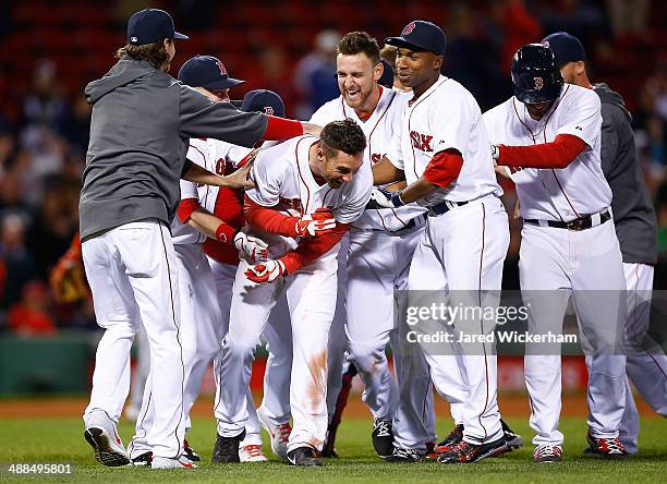 Grady Sizemore of the Boston Red Sox is mobbed by teammates including Will Middlebrooks and Jonathan Herrera ##10 after hitting his walk-off hit in...