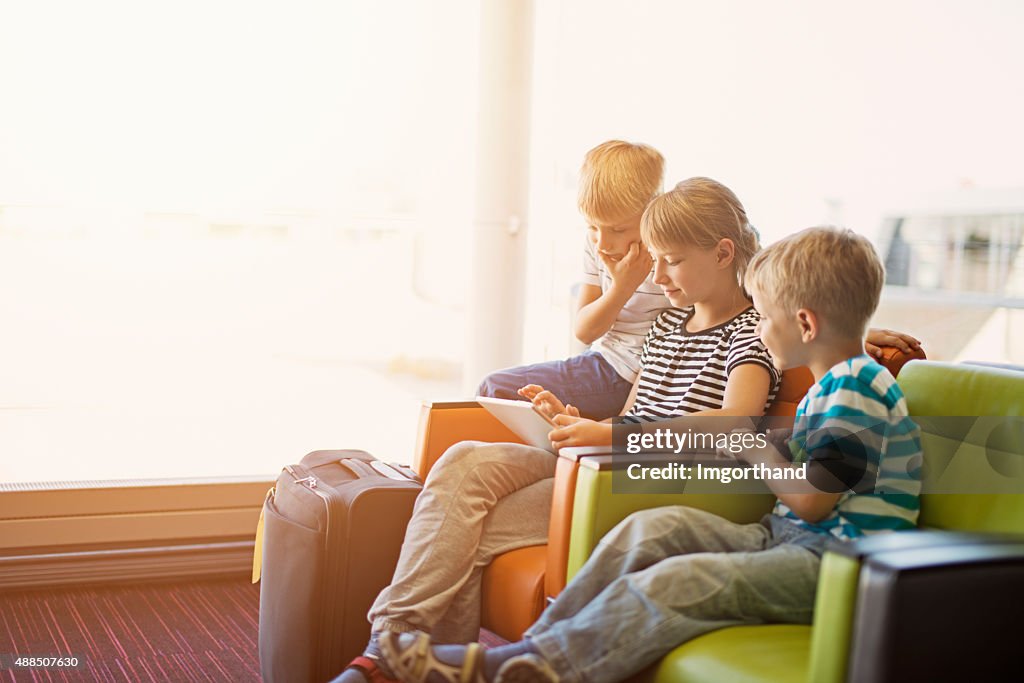 Kids waiting at the Paris airport playing with tablet