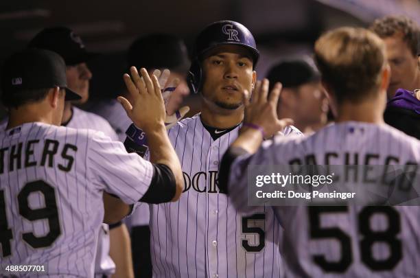 Carlos Gonzalez of the Colorado Rockies celebrates in the dugout with Rex Brothers and Jordan Pacheco after scoring on a double by Nolan Arenado of...