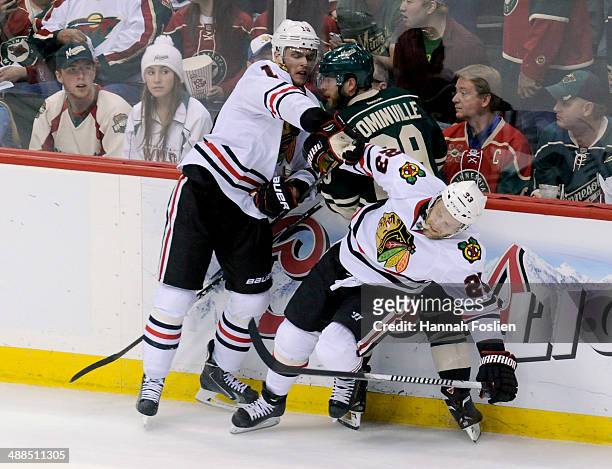 Jonathan Toews and Kris Versteeg of the Chicago Blackhawks check Jason Pominville of the Minnesota Wild into the boards during the third period in...