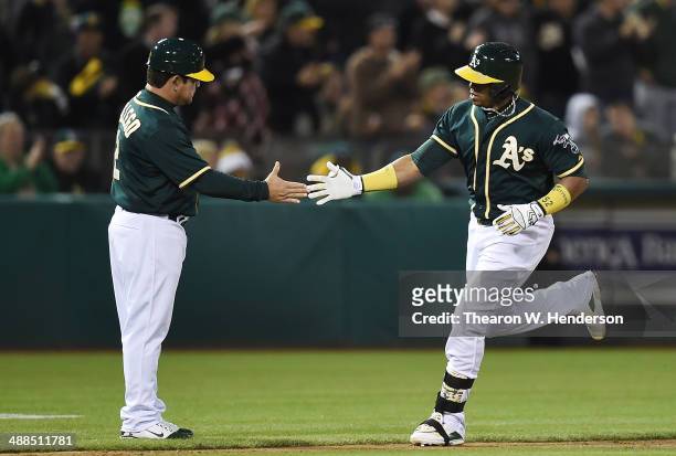 Yoenis Cespedes of the Oakland Athletics trotting around the bases is congratulated by third base coach Mike Gallego after Cespedes hit a solo home...