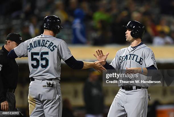 Michael Saunders and Cole Gillespie of the Seattle Mariners celebrate after they scored against the Oakland Athletics in the top of the ninth inning...