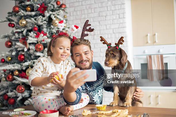 father and daughter in kitchen for christmas with their dog. - papa noel stockfoto's en -beelden