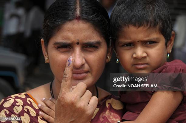 An Indian voter holds up her ink-marked finger after casting her ballot at a polling station in Bollavaram village in Kurnool district, some 250...