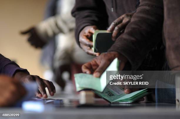 People show their passport prior to vote for the general elections, on May 7, 2014 at a polling station in Marikana. South Africans vote in their...