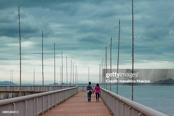 couple walking on wharf - omi stock pictures, royalty-free photos & images