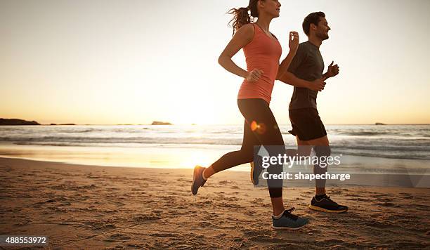 migliorare la forma fisica un passo alla volta. - couple running on beach foto e immagini stock