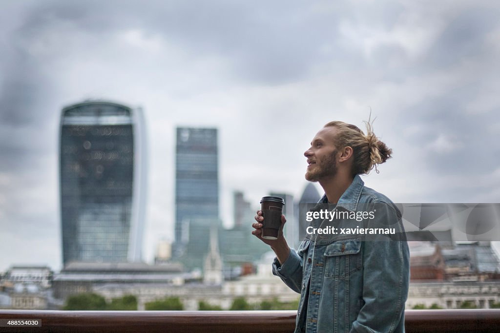 Pensive hipster drinking coffee in the street at London