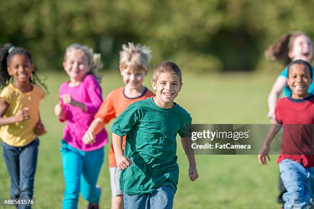 kids running outside for gym class - red shirt stock pictures, royalty-free photos & images